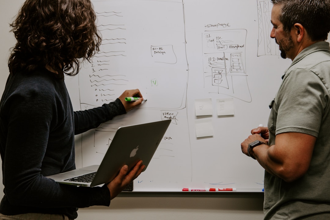 Two men discussing AI integration while standing in front of a whiteboard filled with diagrams and notes.